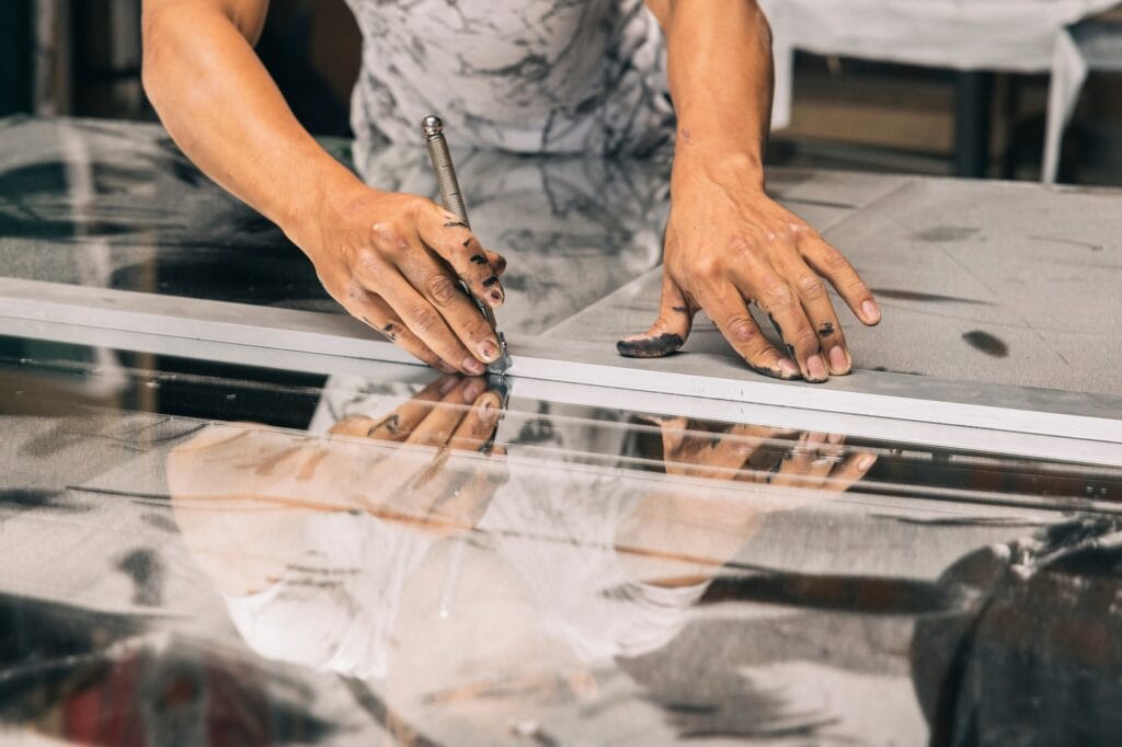 A close up of hands holding a glass cutter