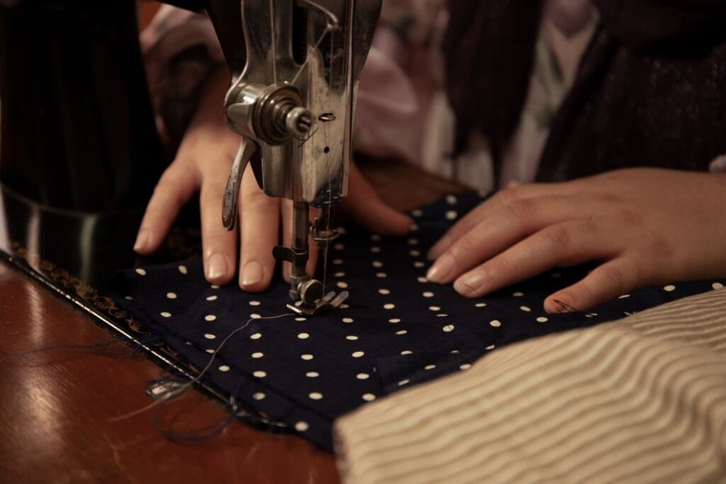 A woman's hands sew a piece of fabric with a sewing machine.