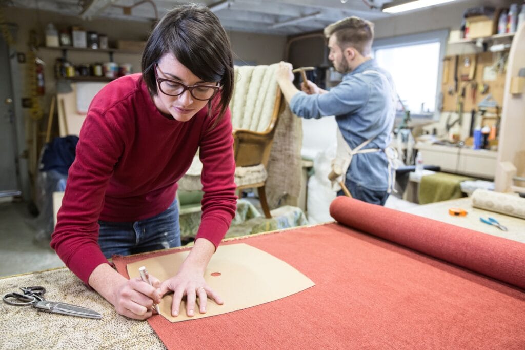 A young Caucasian couple working on a chair as a team of upholsterers.