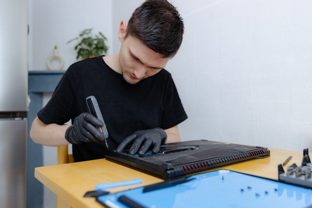 A young man repairs a computer at home.