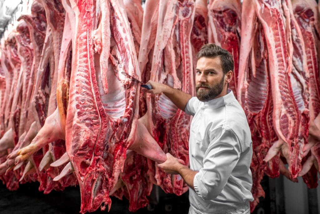 Butcher cutting pork at the manufacturing
