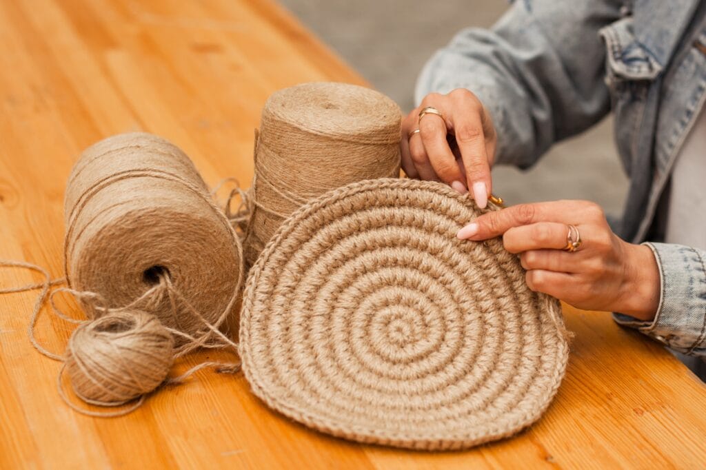 Close-up of a woman's hand knitting product from jute.