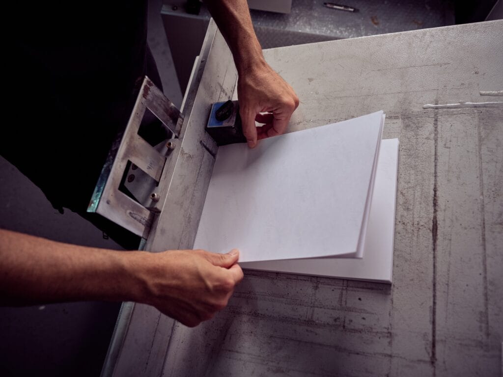 Crop bookbinder working with paper at workbench