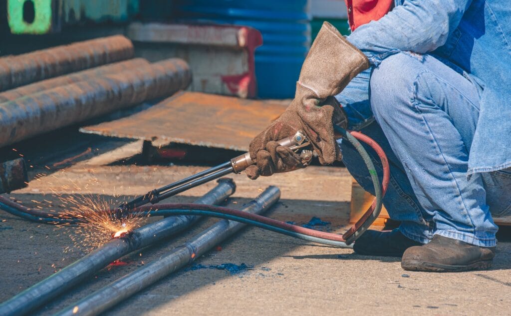 Cropped image of welder is welding galvanized steel pipes with acetylene gas welding torch machine