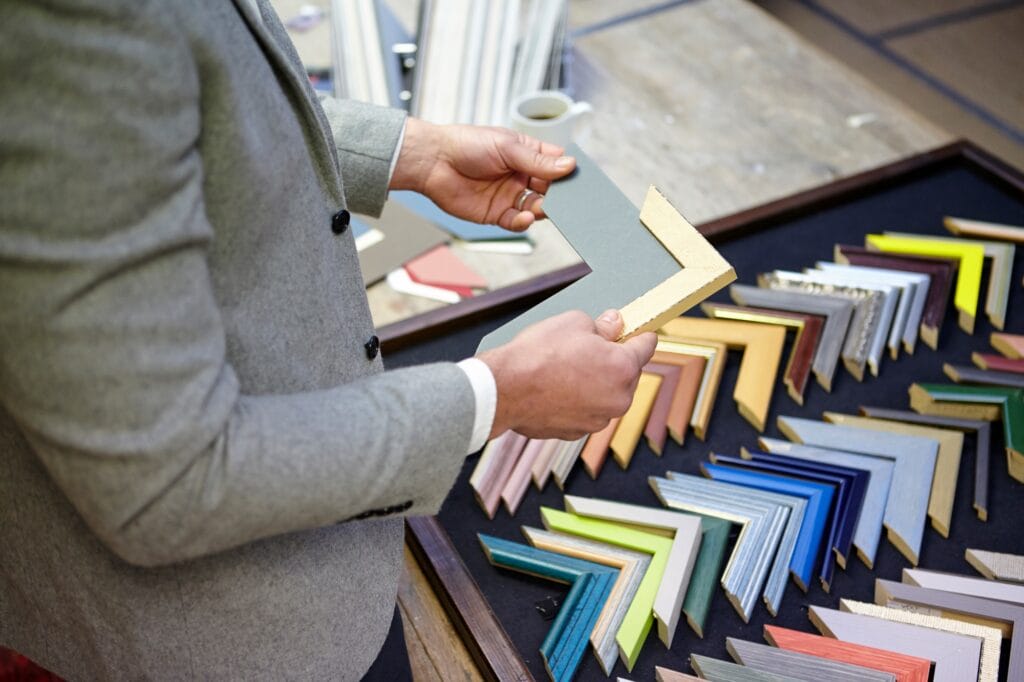 Cropped shot of framer selecting frame in picture framers workshop