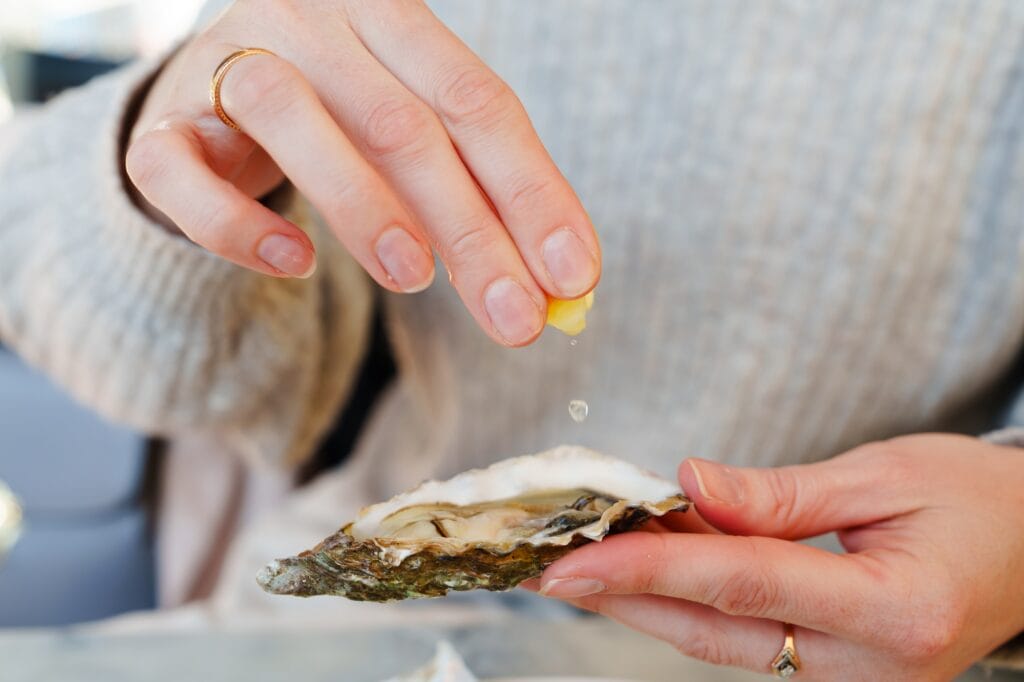 Eating oysters and lemons at an outdoor luxury picnic - a girl enjoying a gastronomic treat