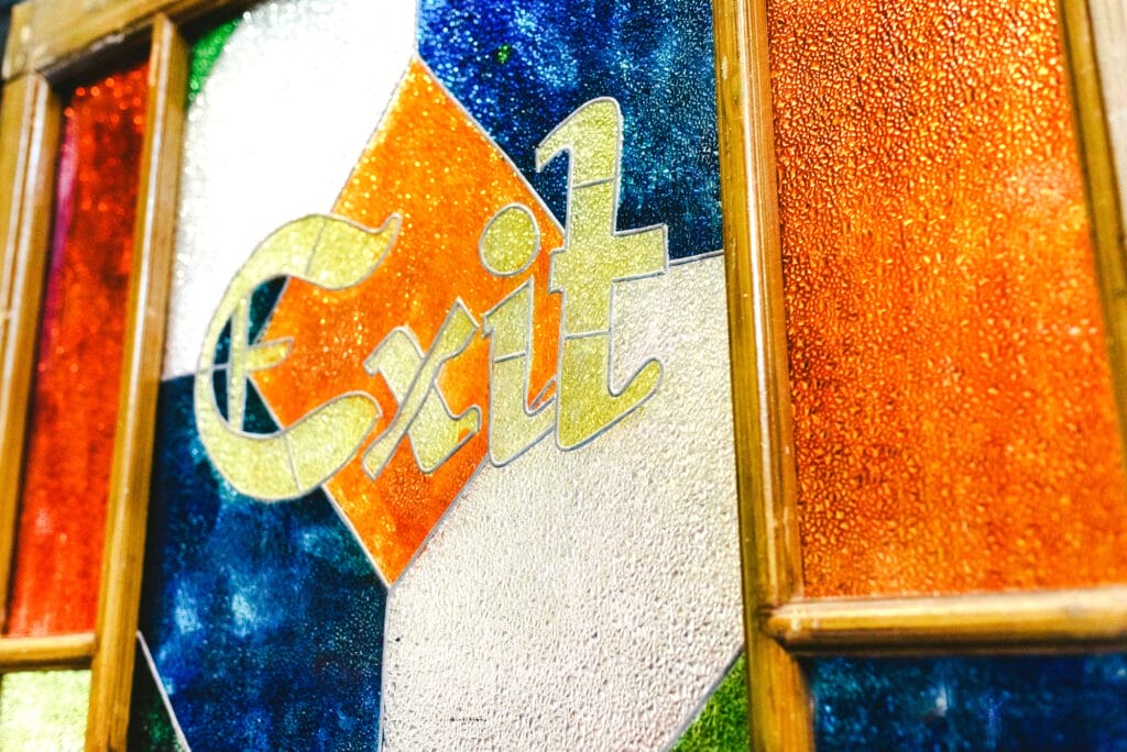 Exit word in an antique engraving on the colorful glass of a door.