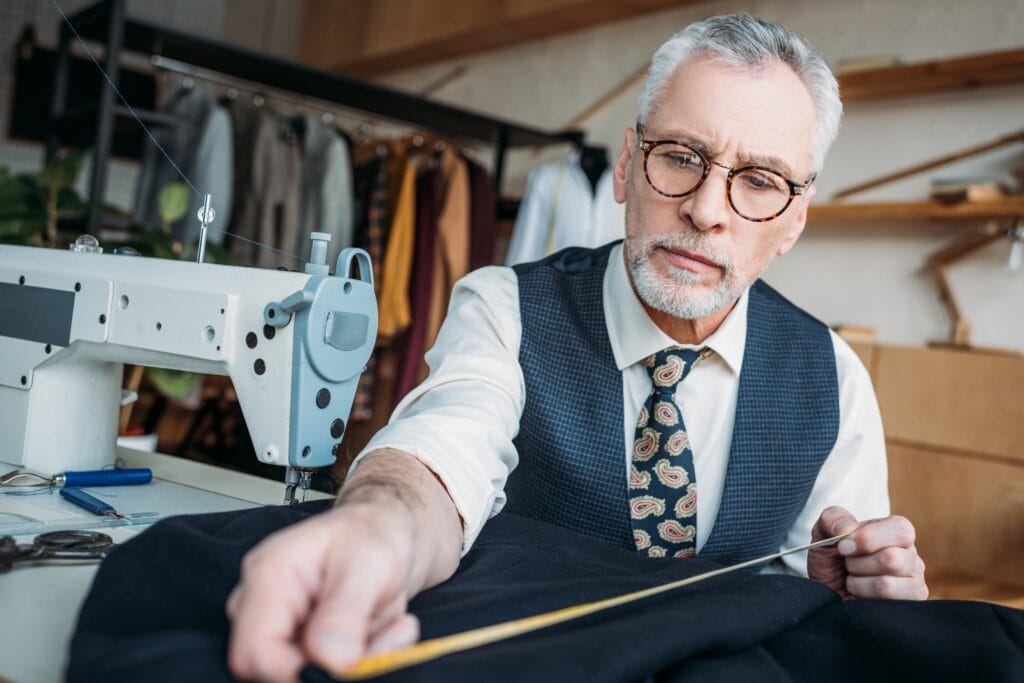 handsome tailor measuring cloth at sewing workshop