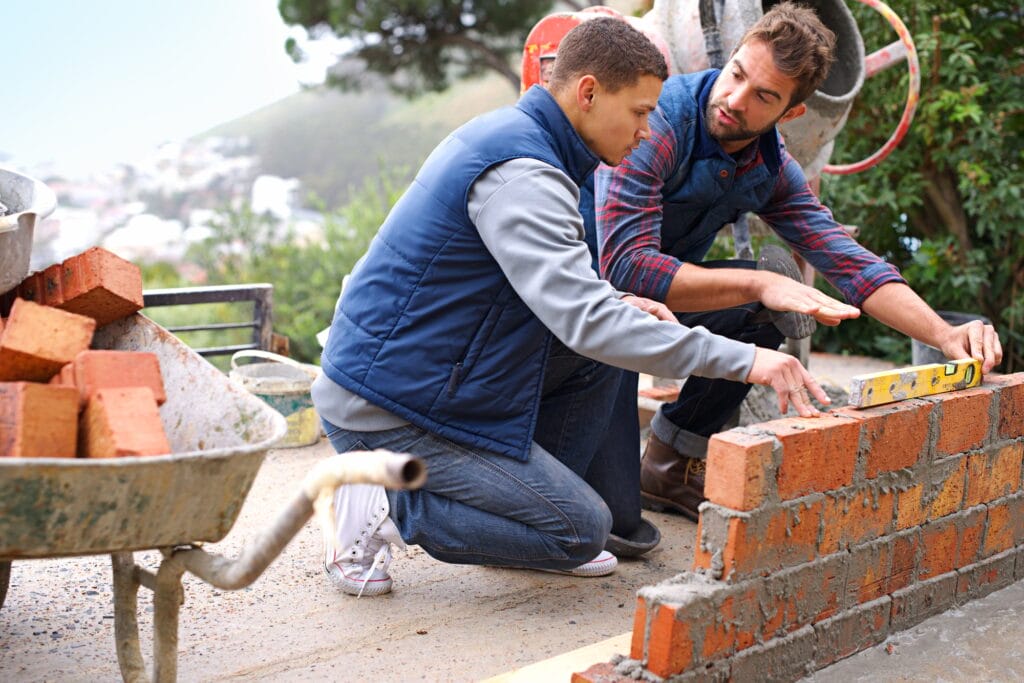Making strong foundations - Teaching the basics. Shot of bricklayers at work.
