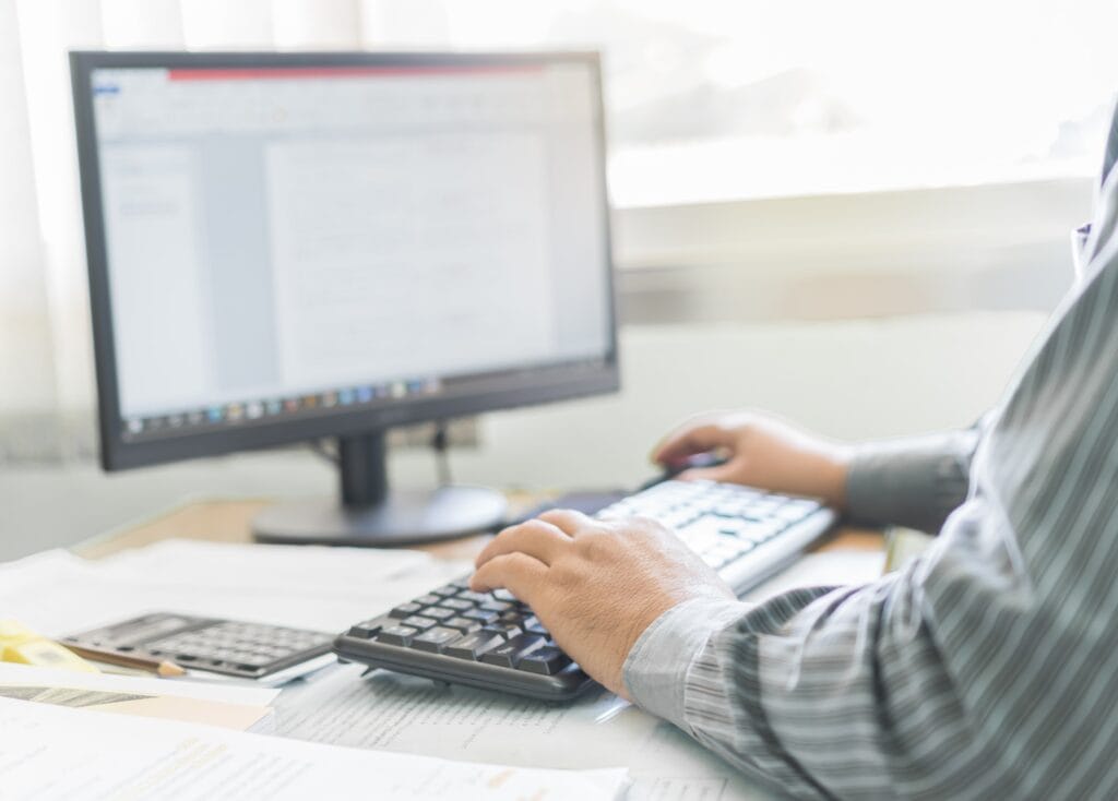 Men hand typing on keyboard in office