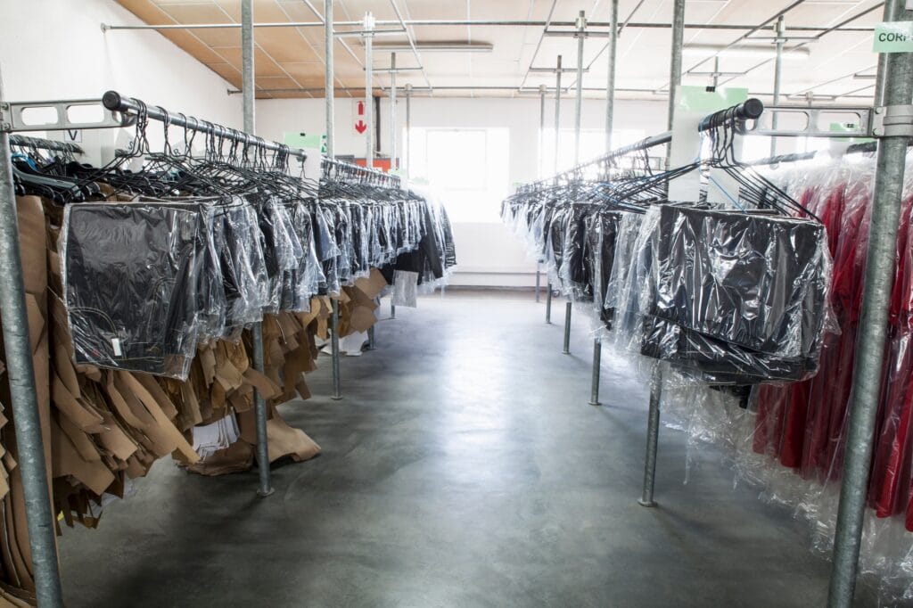 Sewing patterns and garments hanging on clothes rail in sewing factory sample room