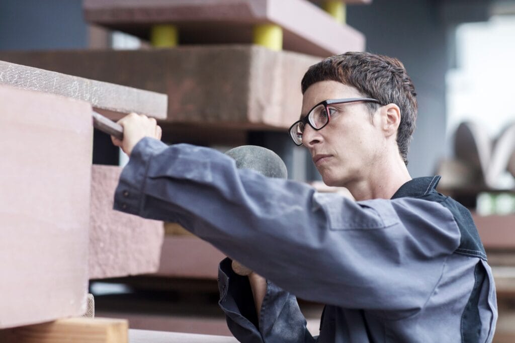 Stonemason using chisel and mallet on block of stone