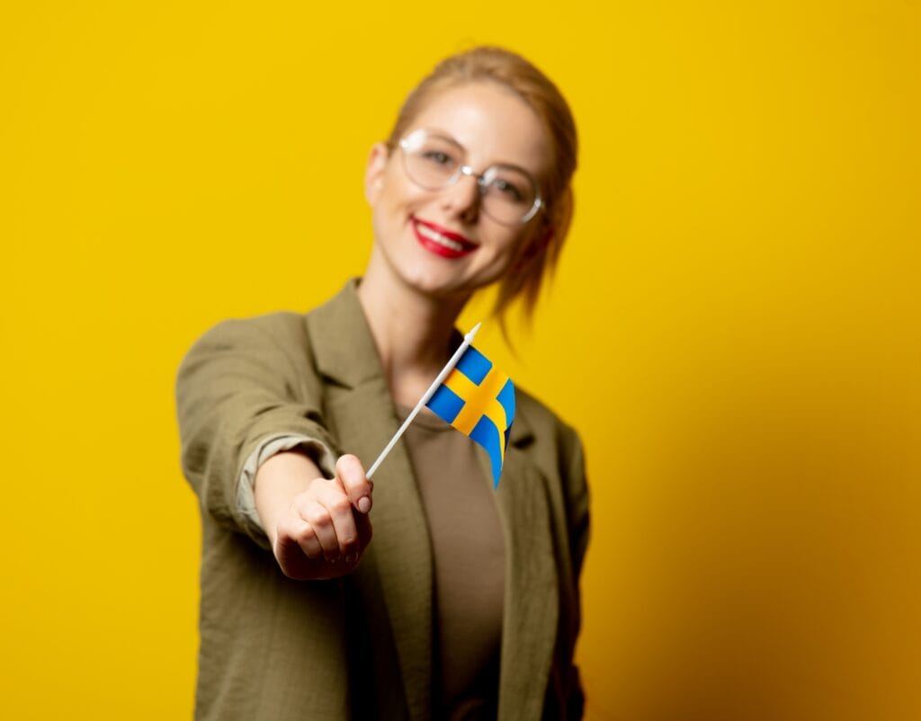 Style blonde woman in jacket with Swedish flag on yellow background
