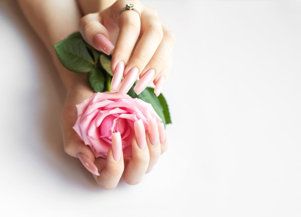 Woman showing pink manicure holding pink rose