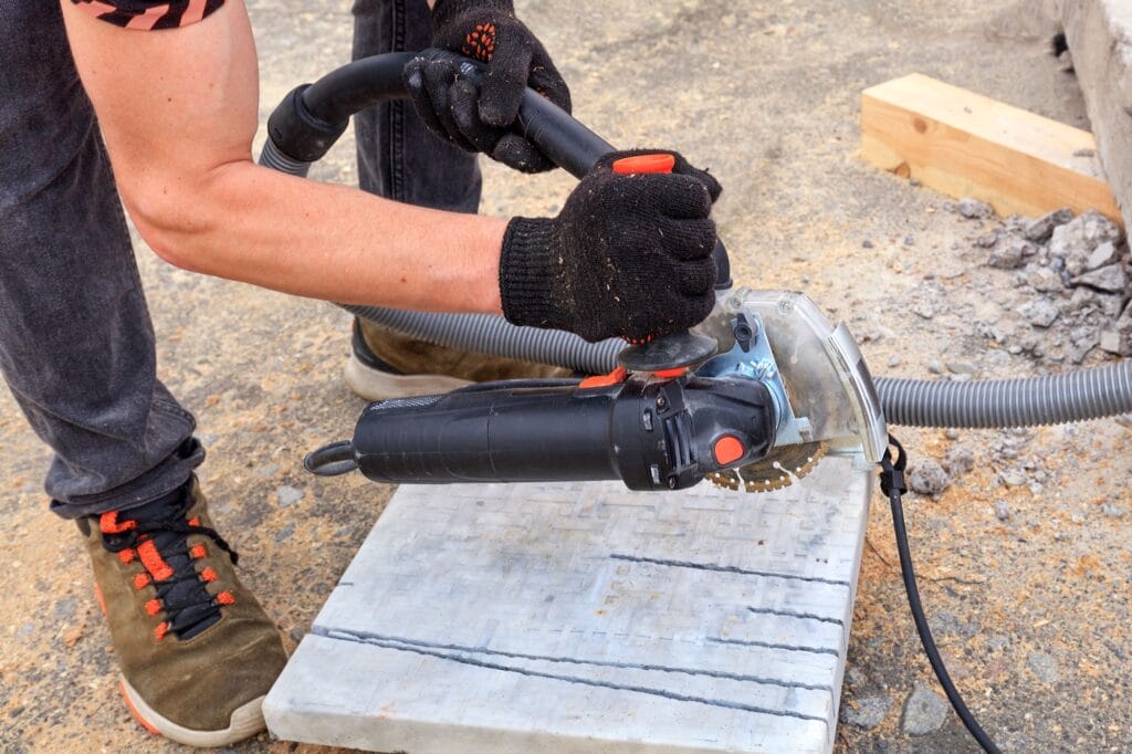 Worker using a diamond cutting disc and an angle grinder to cut the paving bar and metal plate