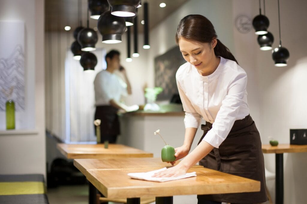 Young waitress wiping table