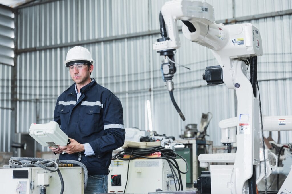 A mechanic is inspecting the oil level in the engine of a machine in a factory