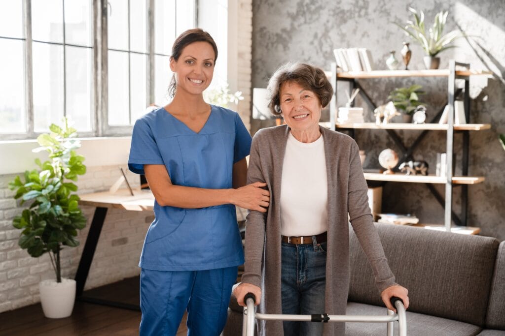Portrait pf happy smiling caretaker nurse helping elderly senior old patient with walking frame.